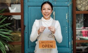 Woman business owner holding "open" sign